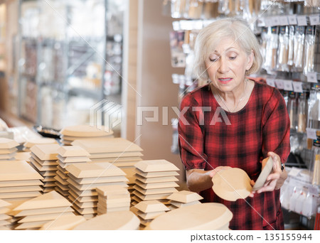 Elderly female customer chooses various wooden molds for future clay molding 135155944