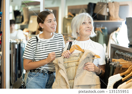 Two women choosing beige vest in clothing store Two women choosing beige vest in clothing store 135155951