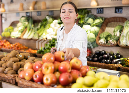 Delighted young woman purchaser choosing apples in grocery store Delighted young woman purchaser choosing apples in grocery store 135155970