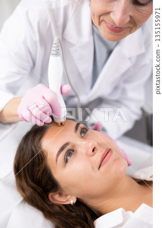 Young woman having face radiolifting procedure made by doctor Young woman having face radiolifting procedure made by doctor 135155971