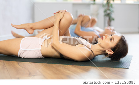 Young woman doing yoga in group in studio 135156095