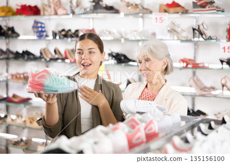 Elderly woman and young woman choosing sneakers in shoe store Elderly woman and young woman choosing sneakers in shoe store 135156100