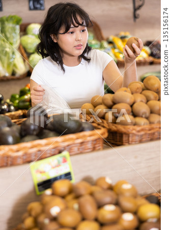 Asian girl choosing fruits in supermarket Asian girl choosing fruits in supermarket 135156174