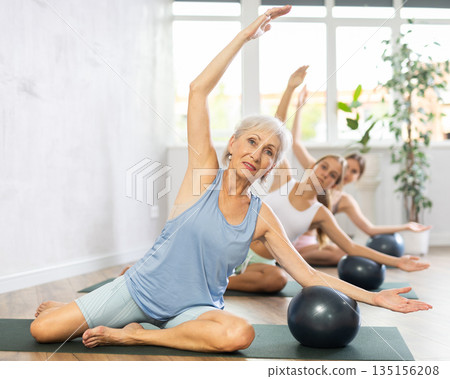 Positive women three generations posing with soft ball pilates at group class in yoga studio Positive women three generations posing with soft ball pilates at group class in yoga studio 135156208