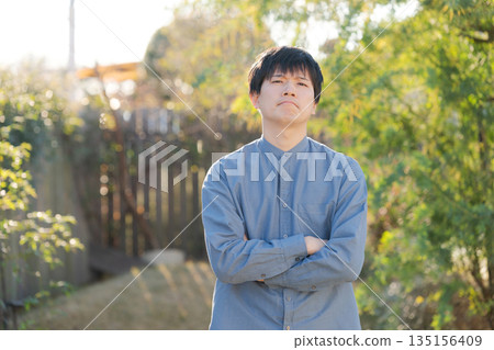 Man standing with his arms crossed in his garden Man standing with his arms crossed in his garden 135156409