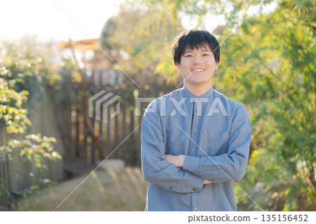 Man standing with his arms crossed in his garden 135156452