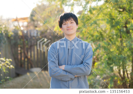 Man standing with his arms crossed in his garden 135156453
