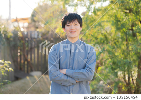Man standing with his arms crossed in his garden 135156454