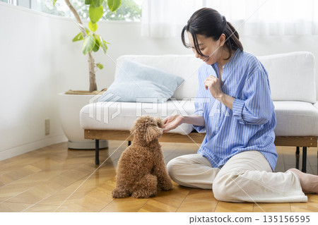 Middle-aged woman training her pet dog Middle-aged woman training her pet dog 135156595
