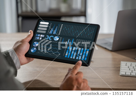 man with Chart businessman reviewing management data as a man tracks chart growth, profit, statistic, and success through business analytics on a tablet. man with Chart businessman reviewing management data as a man tracks chart growth, profit, statistic, and success through business analytics on a tablet. 135157118