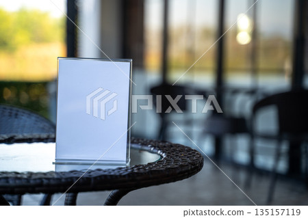 Minimal blank table sign mockup in cafe interior, selective focus and soft light. Perfect for menu design, restaurant promotion and marketing message. 135157119