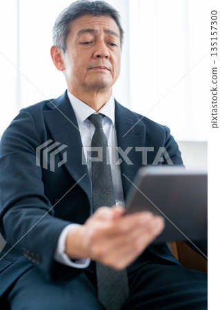 A businessman checking a device while experiencing presbyopia and eye strain A businessman checking a device while experiencing presbyopia and eye strain 135157300
