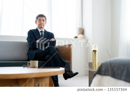一位資深商人雙手交叉放在胸前，神情自信。 135157304