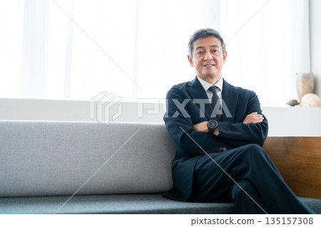 一位資深商人雙手交叉放在胸前，神情自信。 135157308