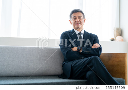 一位資深商人雙手交叉放在胸前，神情自信。 135157309