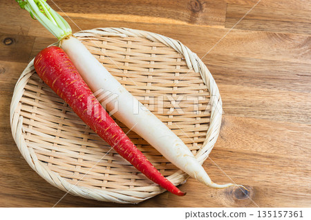A red and white set of Kintoki carrots and zoni daikon radish served on a bamboo basket A red and white set of Kintoki carrots and zoni daikon radish served on a bamboo basket 135157361