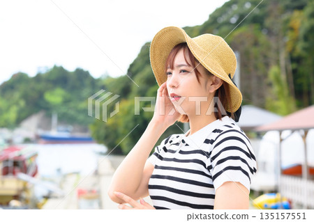 A woman wearing a straw hat looks out at the seaside. (Photo courtesy of Oki Seaside Resort Miyabi) 135157551