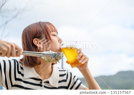 一位女士在戶外享用啤酒和海鮮（照片由沖繩海濱度假村雅提供） 135157567