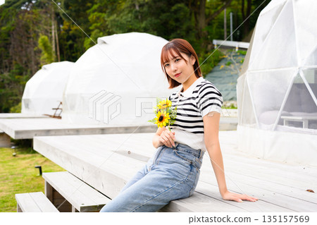 一位女士在豪華露營地手持向日葵（照片由Oki Seaside Resort Miyabi提供） 135157569