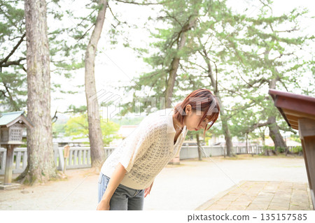 A woman bowing deeply at a shrine A woman bowing deeply at a shrine 135157585