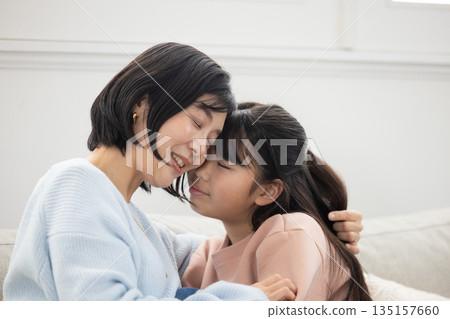 A mother and her elementary school daughter interacting on the living room sofa A mother and her elementary school daughter interacting on the living room sofa 135157660