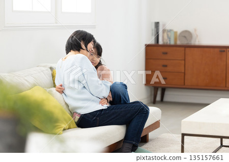 A mother and her elementary school daughter interacting on the living room sofa 135157661