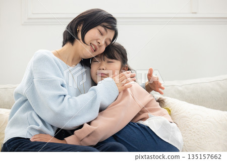 一位母親和她的小學生女兒在客廳沙發上互動 135157662