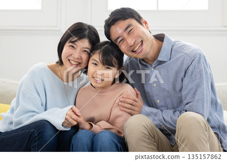幸福的一家三口依偎在沙發上 135157862