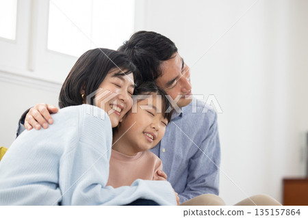 Happy family of three cuddling on the sofa Happy family of three cuddling on the sofa 135157864