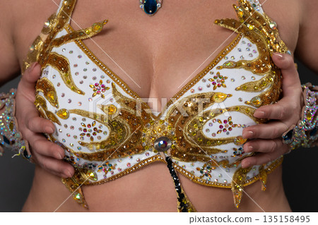 Closeup of woman's breasts in an original designer brassiere that was meticulously crafted and embroidered by hand. Bra meticulously handcrafted in white and gold, adorned with exquisite embroidery 135158495