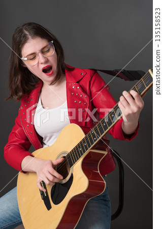 Passionate woman, talented guitarist singer songwriter, performs with incredible heart and soul. Young woman instrumentalist plays guitar, sings rock music, her performance is full of life and energy Passionate woman, talented guitarist singer songwriter, performs with incredible heart and soul. Young woman instrumentalist plays guitar, sings rock music, her performance is full of life and energy 135158523