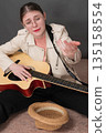 Female street musician with guitar and facial expression stretches out her hand, hoping for donation to play music. Her desperate face is directed at camera, conveying sense of hope and anticipation Female street musician with guitar and facial expression stretches out her hand, hoping for donation to play music. Her desperate face is directed at camera, conveying sense of hope and anticipation 135158554