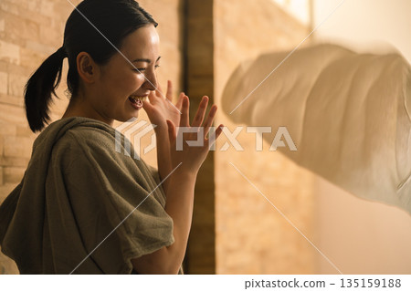 A young man applying heat waves to a young woman with a towel. Beauty image 135159188
