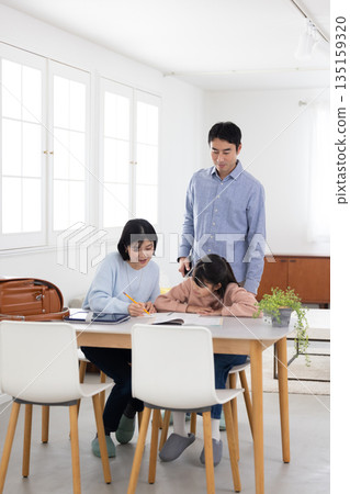 Elementary school girl enjoying learning at home with her parents Elementary school girl enjoying learning at home with her parents 135159320