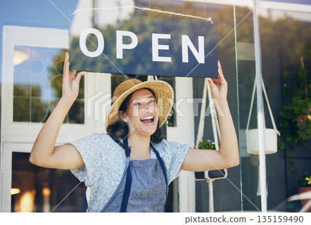 Portrait, plant nursery and open with a woman hanging a sign in the window of her shop for gardening. Small business, garden center and an excited young female florist opening her new flower store Portrait, plant nursery and open with a woman hanging a sign in the window of her shop for gardening. Small business, garden center and an excited young female florist opening her new flower store 135159490