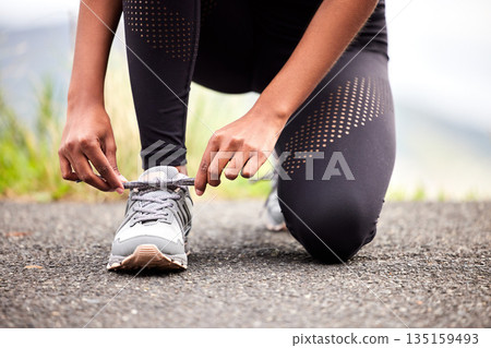 Sport, feet of woman tying sneakers and runner on road for safety during outdoor marathon training. Running, cardio health and wellness, female athlete fixing laces on footwear and closeup of asphalt Sport, feet of woman tying sneakers and runner on road for safety during outdoor marathon training. Running, cardio health and wellness, female athlete fixing laces on footwear and closeup of asphalt 135159493