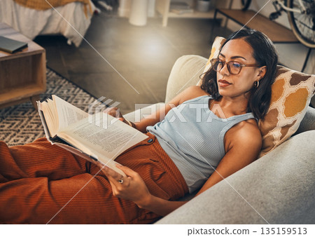 Woman relax on sofa, reading book at house and break on the weekend with literature, fantasy story and peace. Female person with hobby, leisure and chill at home, read for knowledge and information 135159513