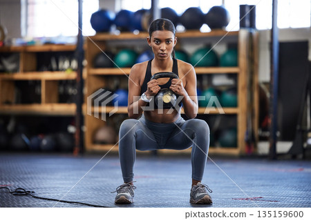 Portrait of woman in gym, kettlebell and squat for weightlifting, power and muscle with focus at sports club. Balance, fitness and fit female bodybuilder lifting weights and training with health goal 135159600