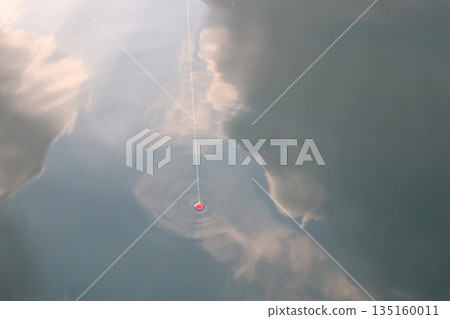Clouds reflected in the sea, fishing line and float 135160011