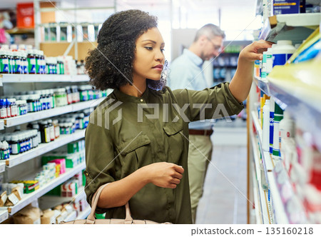 Pharmacy, health shopping and woman with medicine check and product in a retail store. Pharmaceutical, drugs and pills with a African female person looking at box for ingredients and info in shop Pharmacy, health shopping and woman with medicine check and product in a retail store. Pharmaceutical, drugs and pills with a African female person looking at box for ingredients and info in shop 135160218