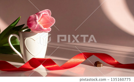 Pink Tulip In Heart Mug With Red Ribbon And Chocolate Piece, Romantic Still Life. Pink Tulip In Heart Mug With Red Ribbon And Chocolate Piece, Romantic Still Life. 135160775