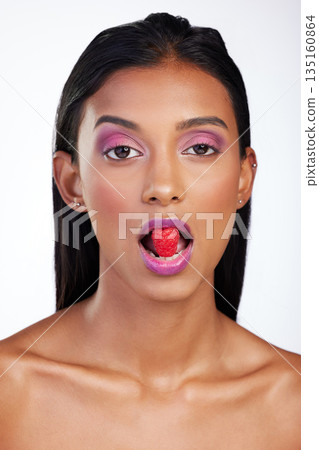 Woman, makeup and raspberry in mouth for studio portrait, glow color and skincare by white background. Face of indian model eating fruits with bold cosmetics, facial aesthetic and shine for beauty Woman, makeup and raspberry in mouth for studio portrait, glow color and skincare by white background. Face of indian model eating fruits with bold cosmetics, facial aesthetic and shine for beauty 135160864