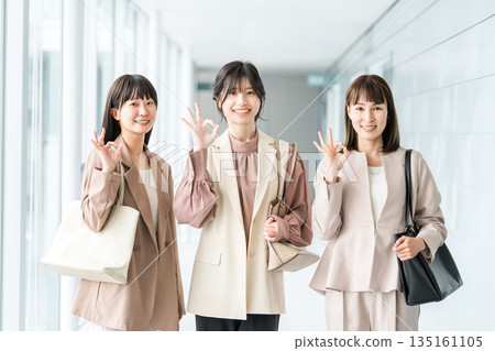 Smiling businesswomen lined up in the office (working women, working mothers) 135161105