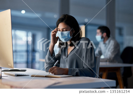 Call center, woman and notebook at computer with mask for customer support, sales and CRM consulting at night. Female agent, telemarketing and virus protection on face in office for administration 135161254