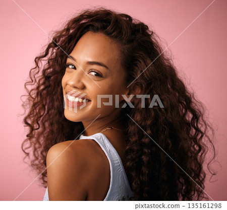 Health, hair care and portrait of a woman in a studio with a natural, long and curly hairstyle. Happy, smile and brunette female model with beauty keratin salon treatment isolated by pink background. Health, hair care and portrait of a woman in a studio with a natural, long and curly hairstyle. Happy, smile and brunette female model with beauty keratin salon treatment isolated by pink background. 135161298