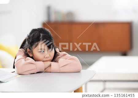 An elementary school girl with a sad expression lying on the table An elementary school girl with a sad expression lying on the table 135161455
