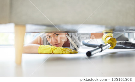 Vacuum, floor and cleaning with a woman housekeeper using equipment to remove bacteria in a home. Safety, sofa and hygiene with a young female cleaner working in a house living room for service 135161508
