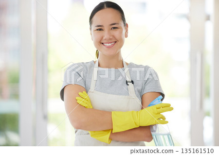 Portrait, cleaning and arms crossed with a woman housekeeper using disinfectant to remove bacteria in a home. Safety, smile and hygiene with a confident young female cleaner working in a living room 135161510