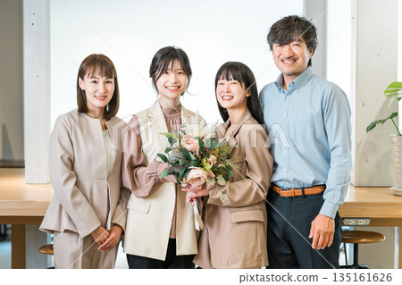 一位微笑的女商人收到一束鮮花，她的團隊成員鼓掌。 135161626