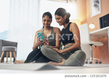 Exercise, phone and women together on home floor with internet for social media app. Indian sisters or female friends in lounge with smartphone for online class, chat or fitness workout with partner Exercise, phone and women together on home floor with internet for social media app. Indian sisters or female friends in lounge with smartphone for online class, chat or fitness workout with partner 135161870